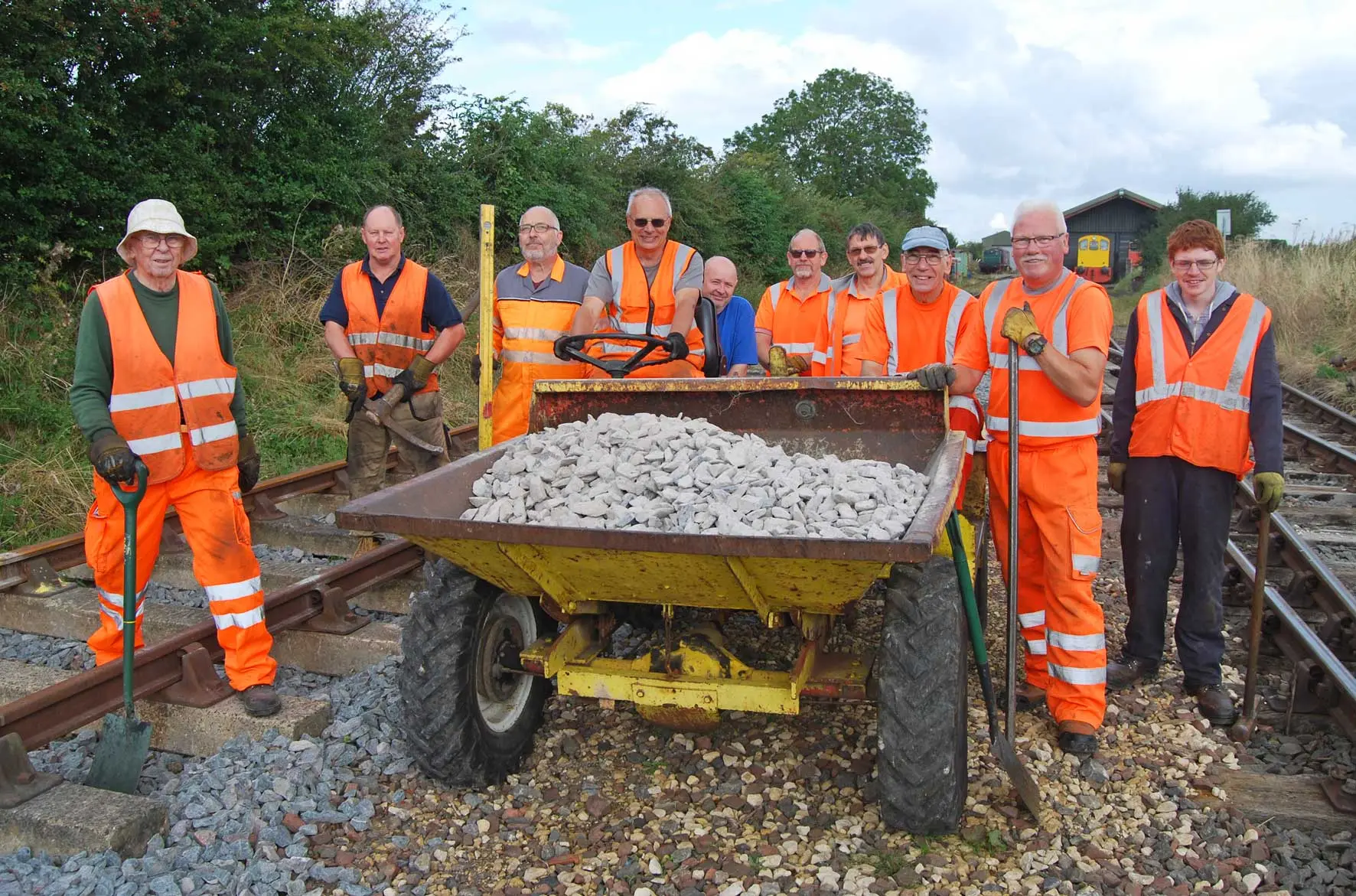 Volunteers in high-visibility clothing with a dumper of ballast on the line